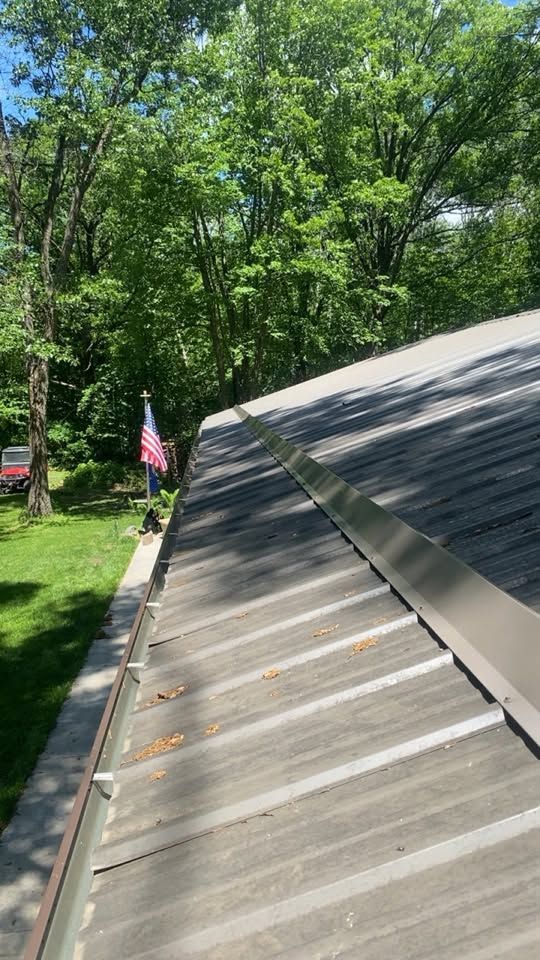 Roof shingles under repair beside a wooded yard with an American flag