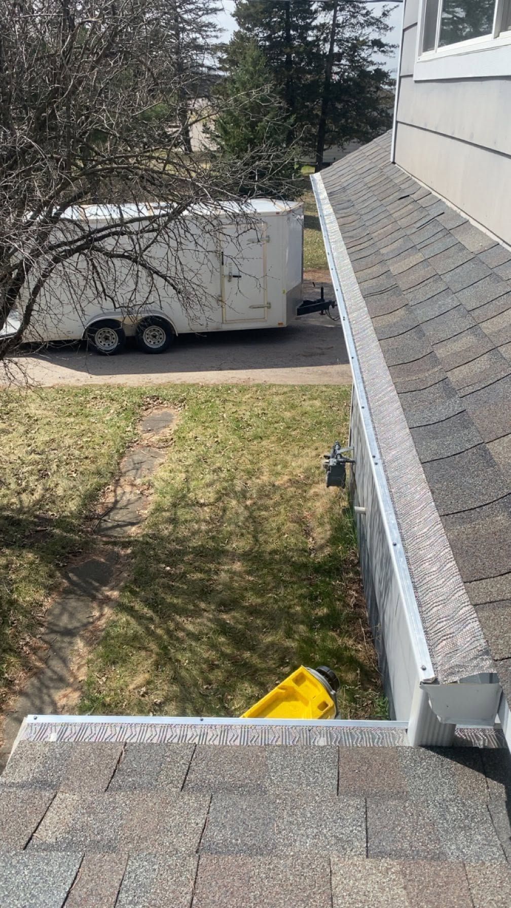Rooftop view of a white truck parked beside a building, with trees and a grassy yard below.