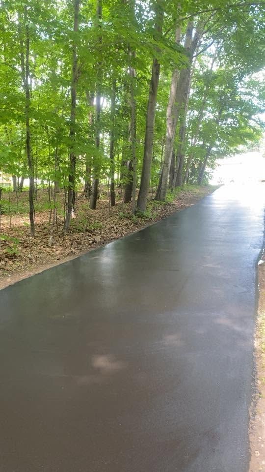 Wet paved path through a wooded area on a rainy day