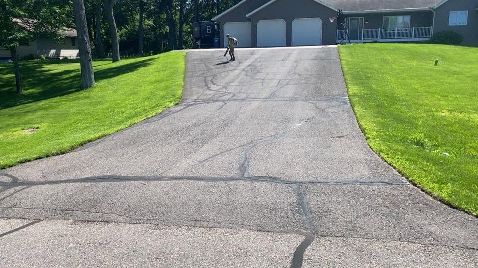 Long driveway leading to a two-car garage, with green lawns on both sides.