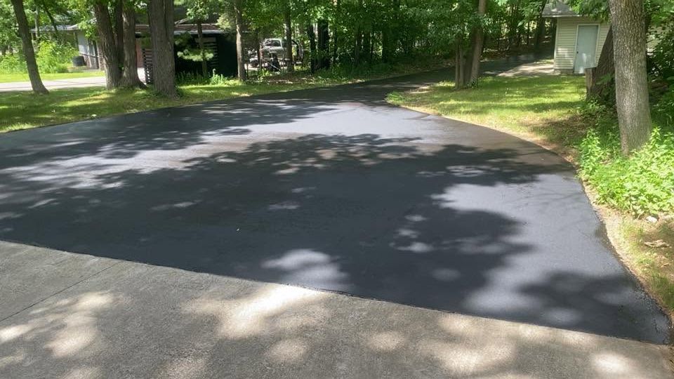 Freshly paved curved road in a wooded park with sunlight and tree shadows