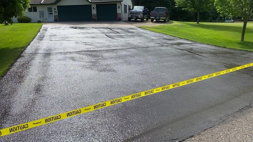 Police tape across a wet driveway in front of a house and garage