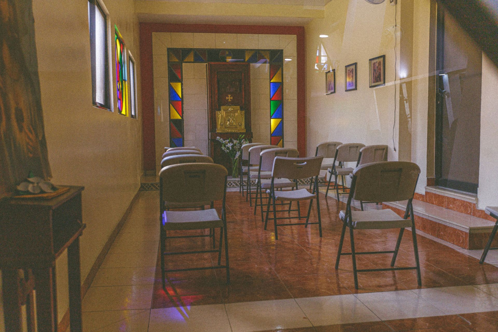 Interior chapel with rows of chairs, stained glass, and an altar.