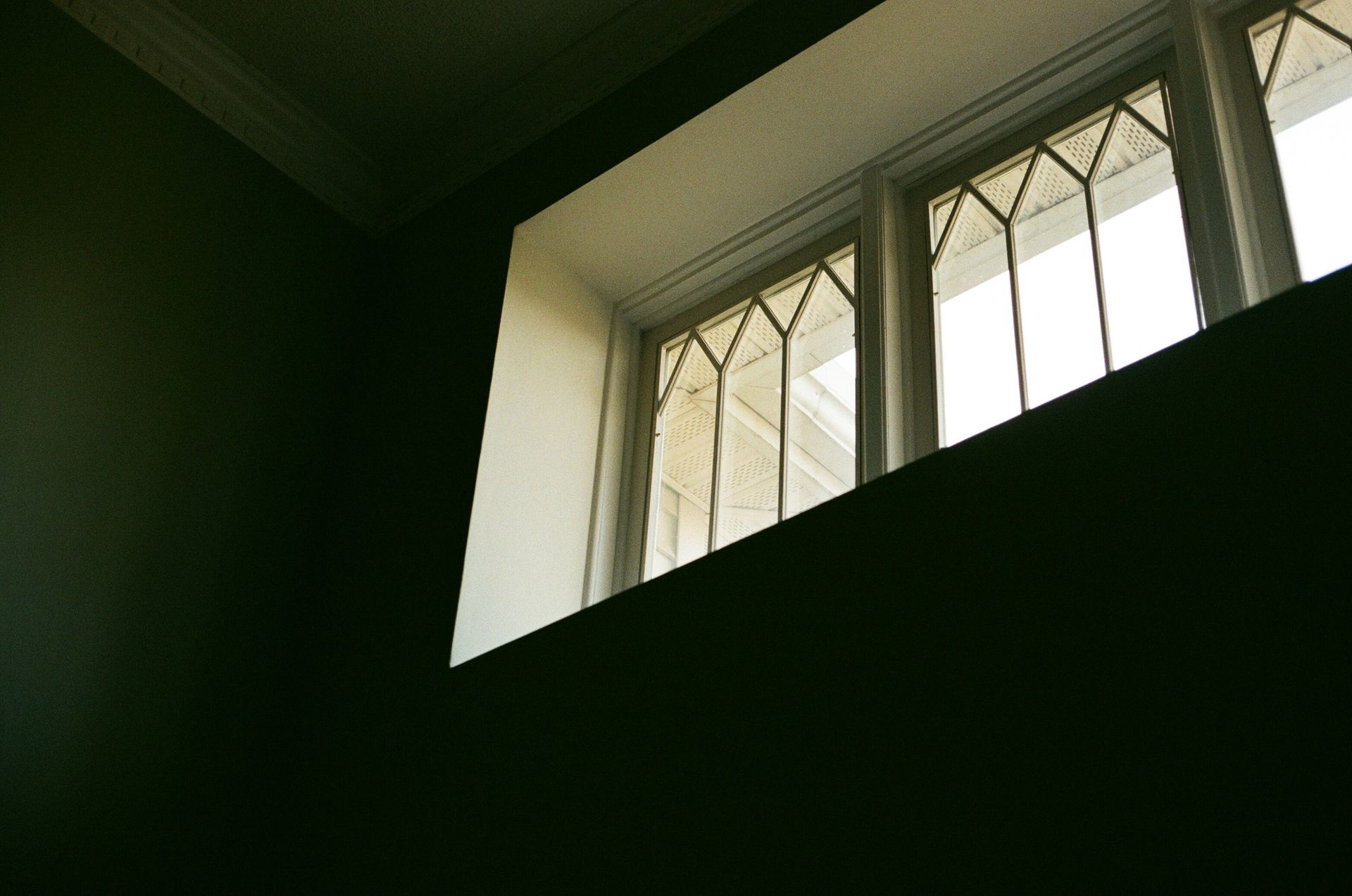 Window with geometric grid and ornate details, set in dark walls.