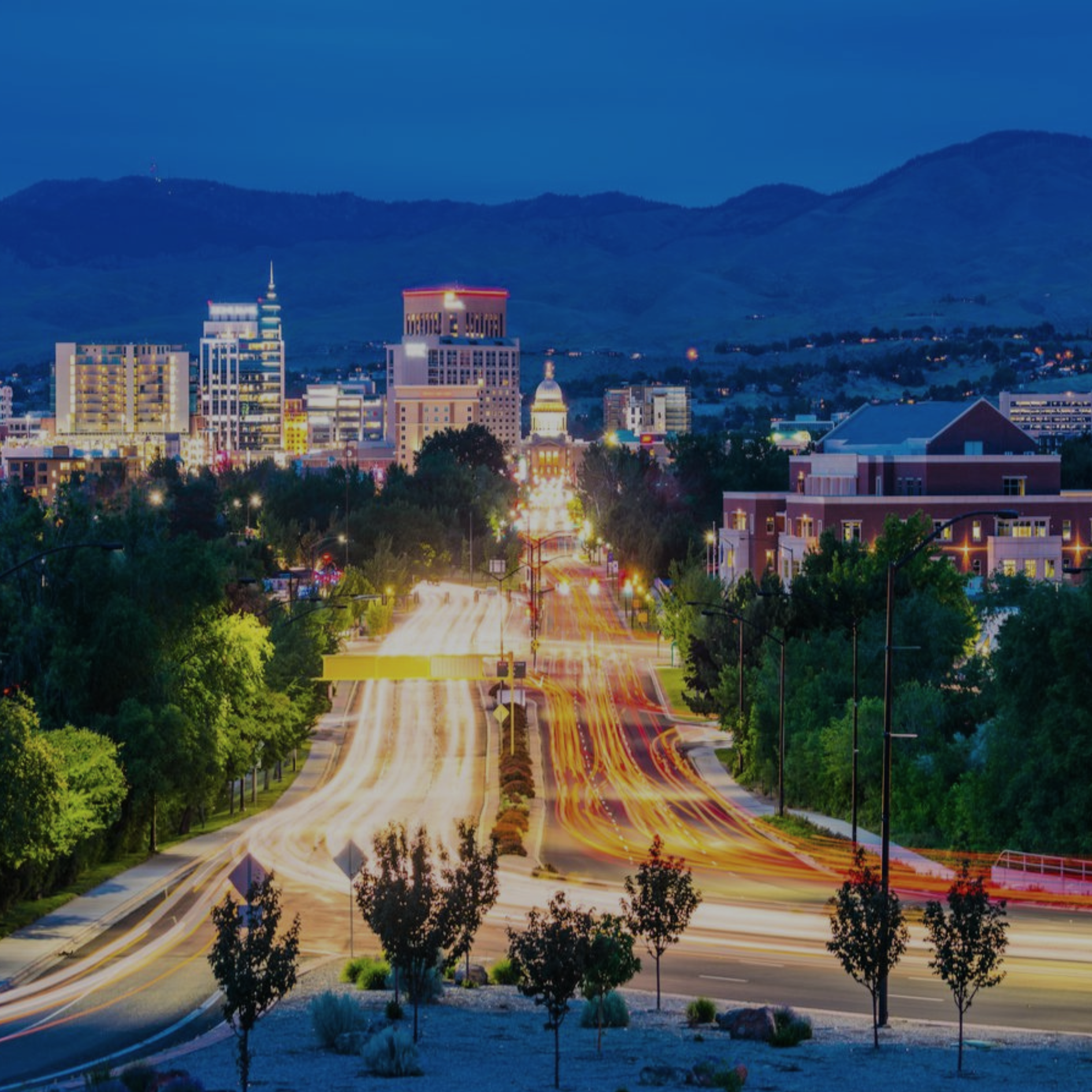 Caldwell Boise, Idaho skyline at dusk with traffic lights streaking toward the state capitol building.