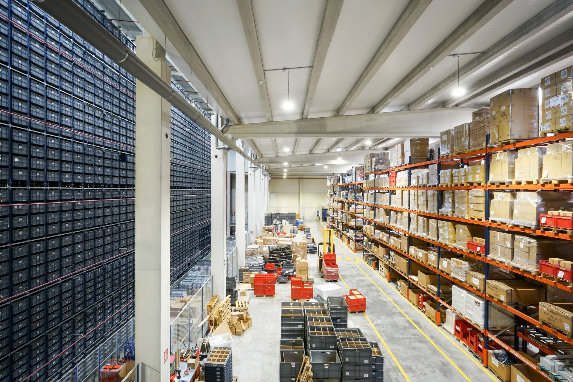 Warehouse interior with tall shelves, filled with boxes. Forklift moving items.