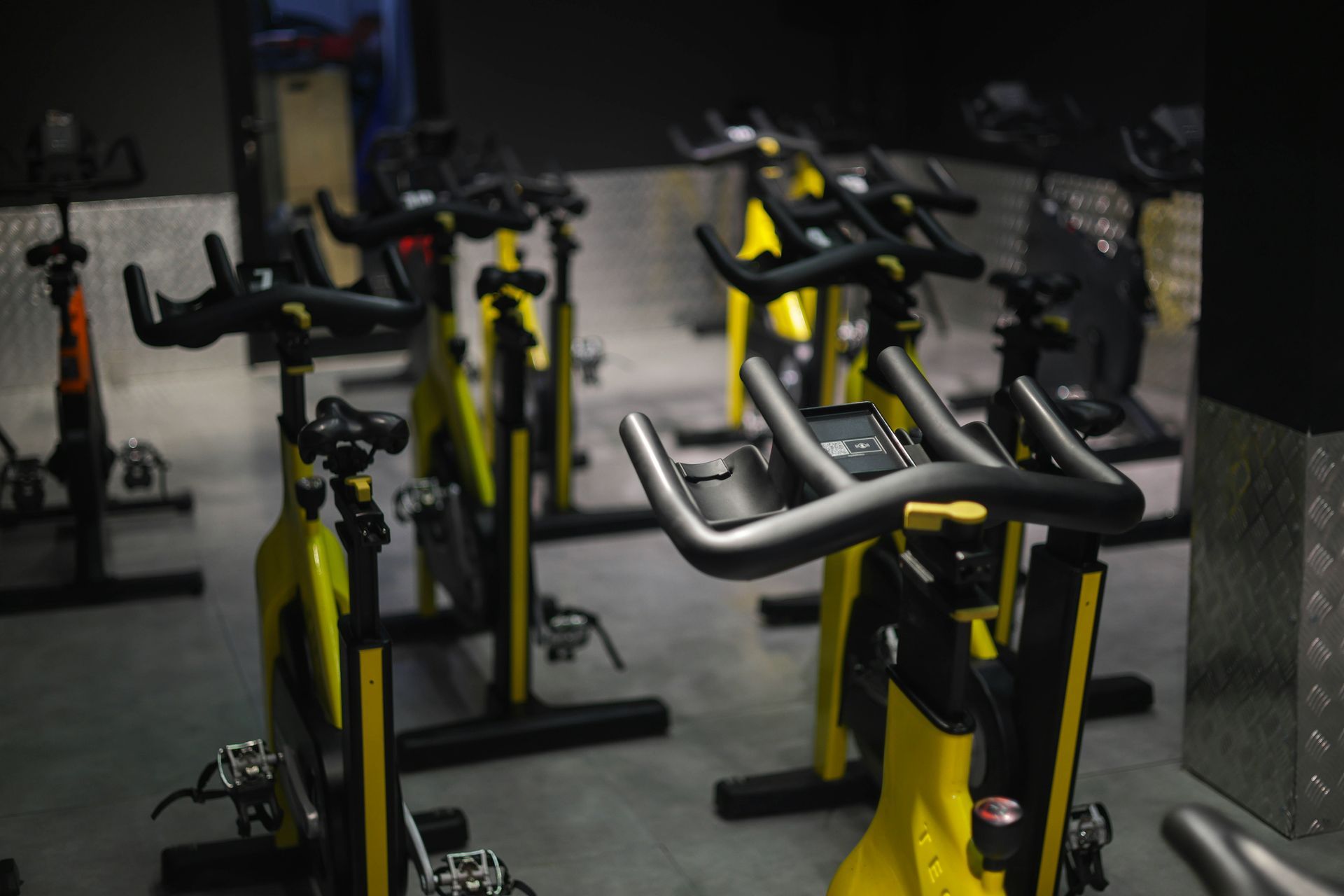 Indoor cycling bikes in a dimly lit studio, mostly yellow and black.