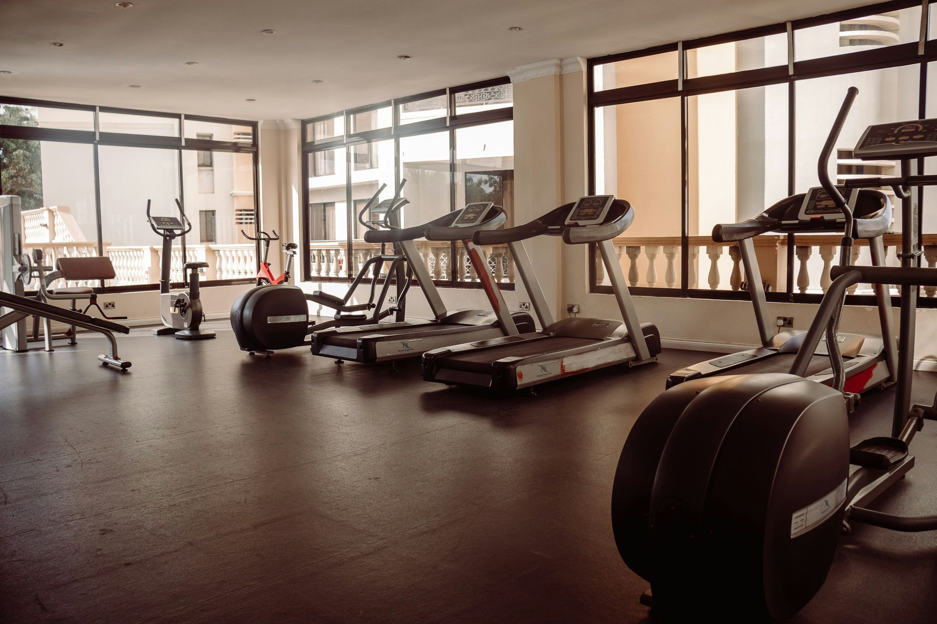 Gym with cardio machines, treadmills, and exercise bikes. Windows provide outside view.