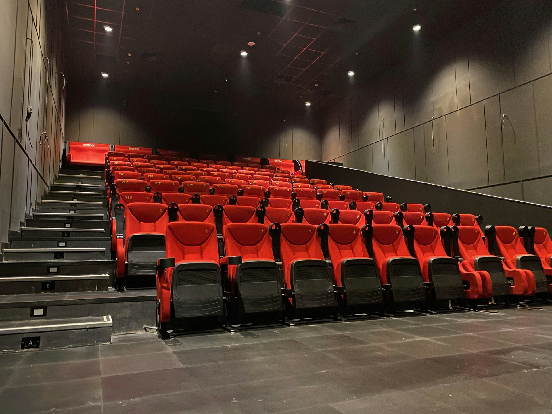 Empty movie theater with red seating and black walls.