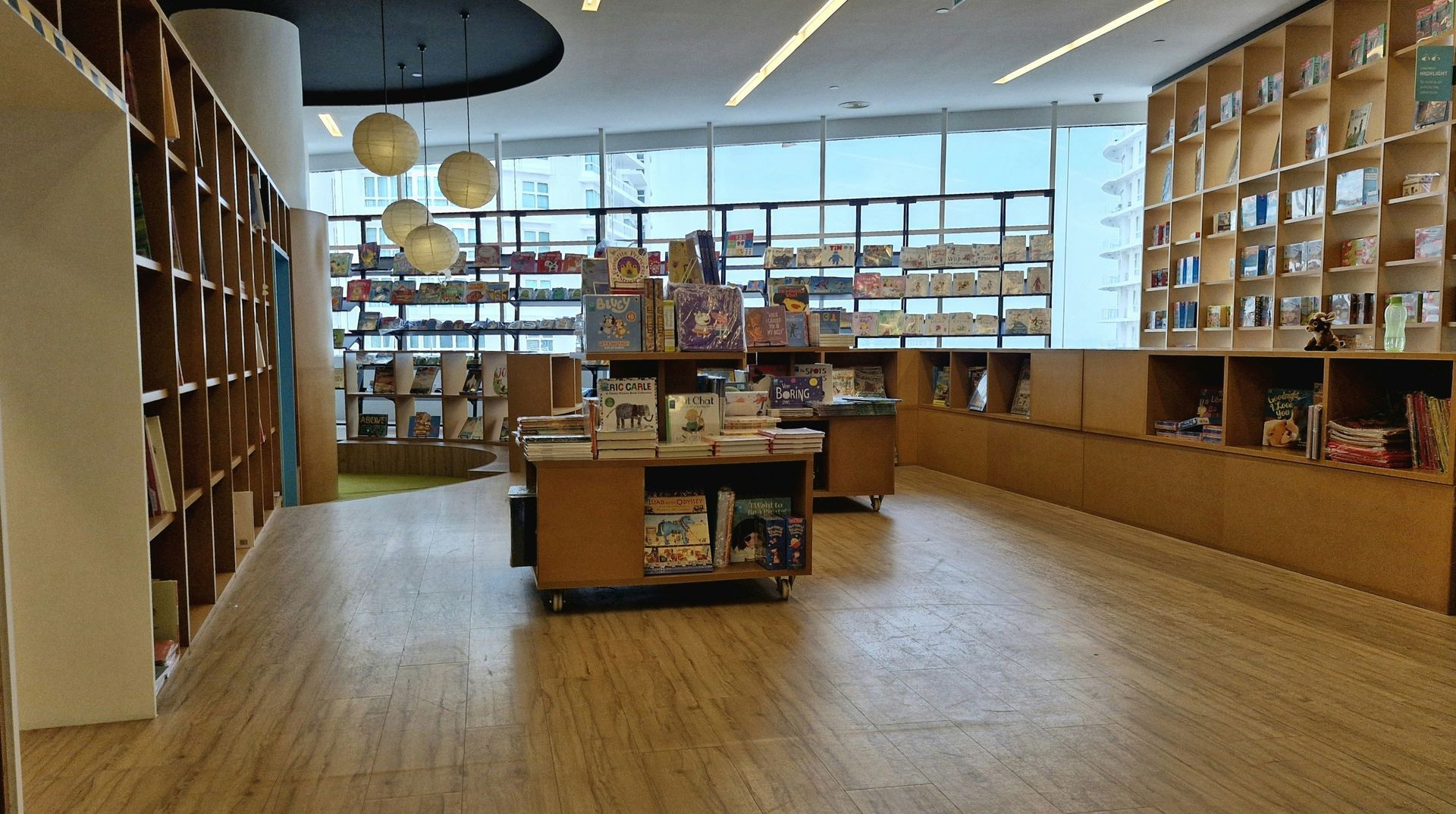 Bookstore interior with wooden shelves, books, and display tables under bright lights.