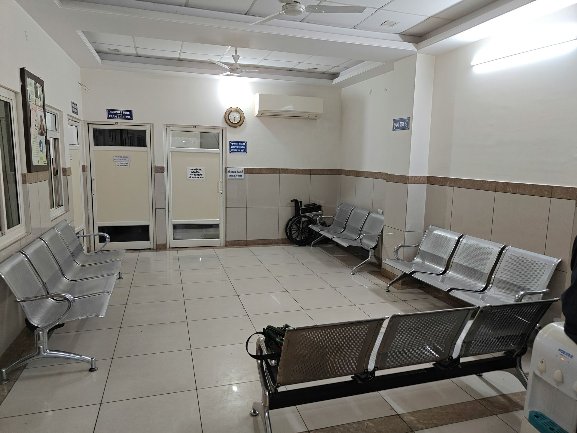 Waiting room with metal chairs, tiled floor, and doors.