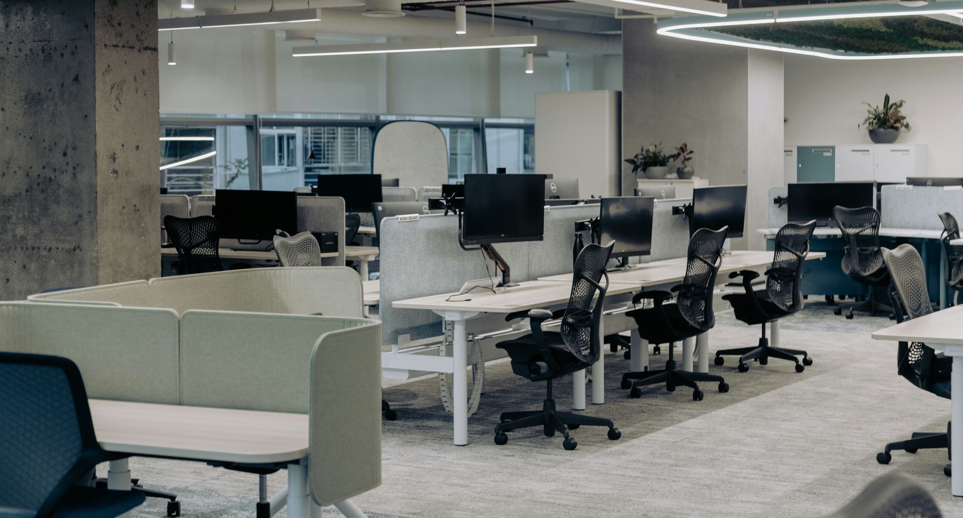 Office with open workspaces, computer desks, office chairs, and modular partitions.