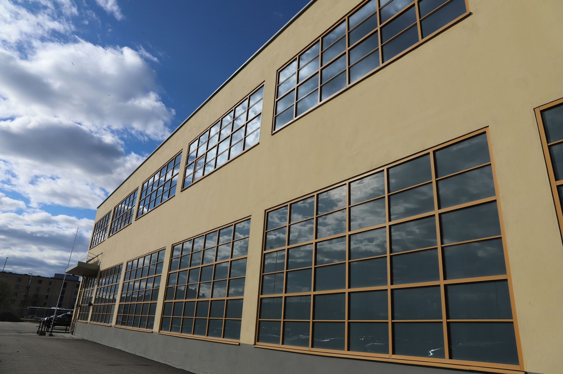 Beige building with large windows reflecting blue sky and clouds.