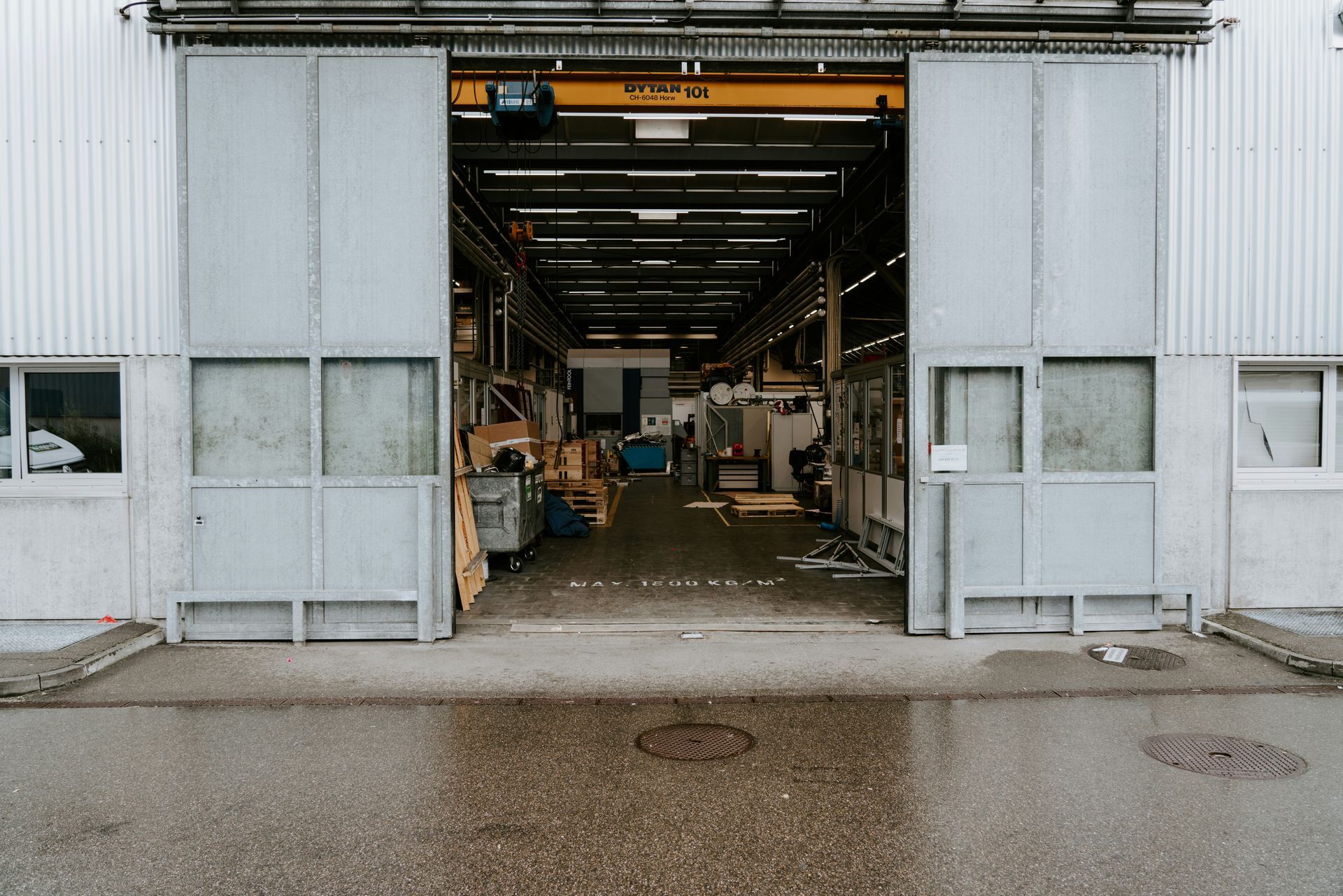 Large factory entrance with open gray doors, revealing the interior of the industrial space.