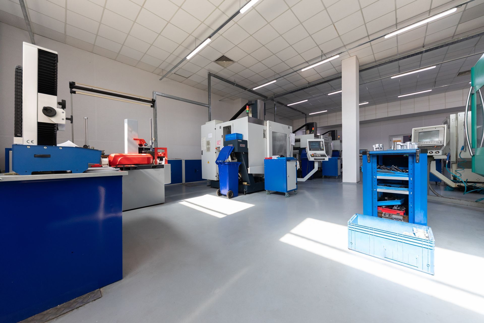 A brightly lit industrial workshop with blue machines and equipment.
