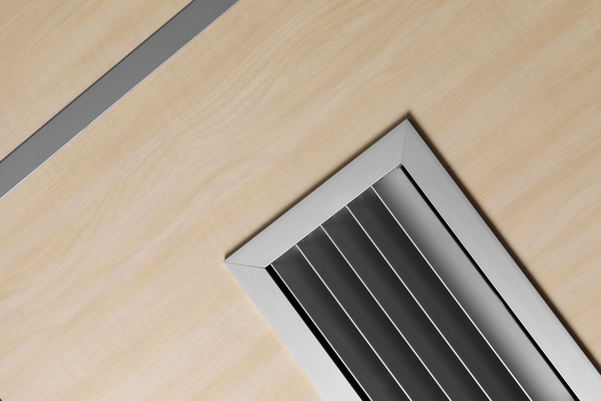 Close-up of a wooden surface with a rectangular air vent and a silver trim.