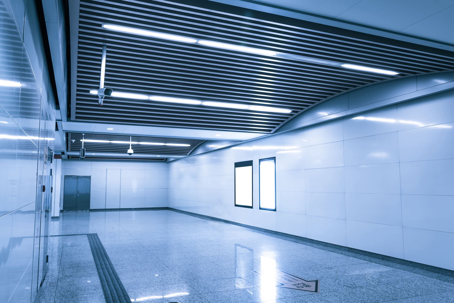 Modern subway station interior with bright lights, glossy floor, and blank advertising displays.