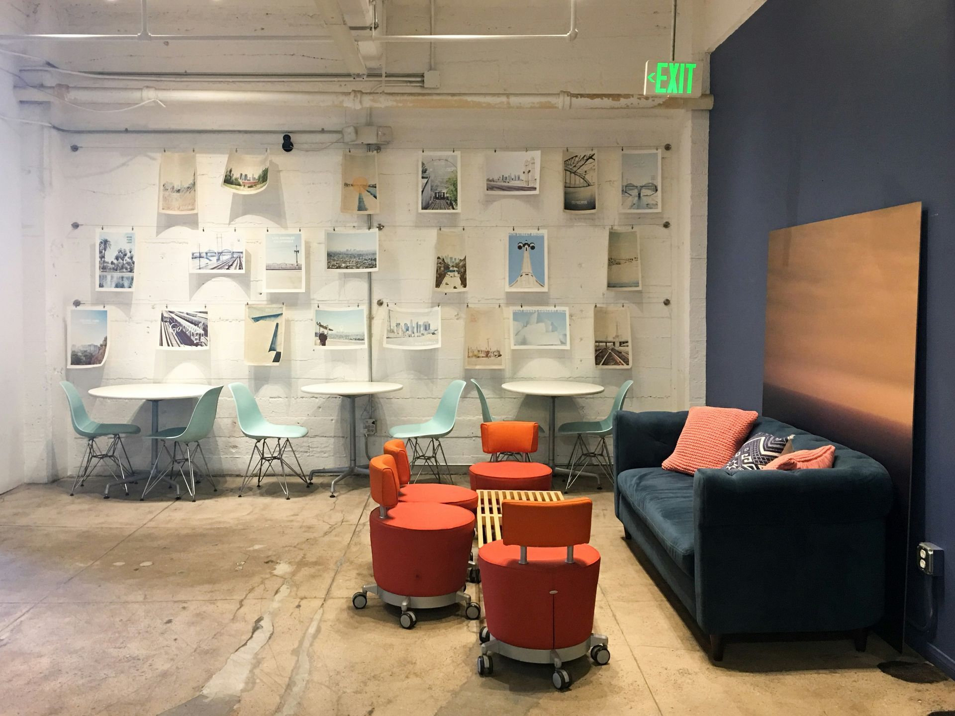 A colorful office waiting area with round tables, chairs, sofa, and art on the wall.