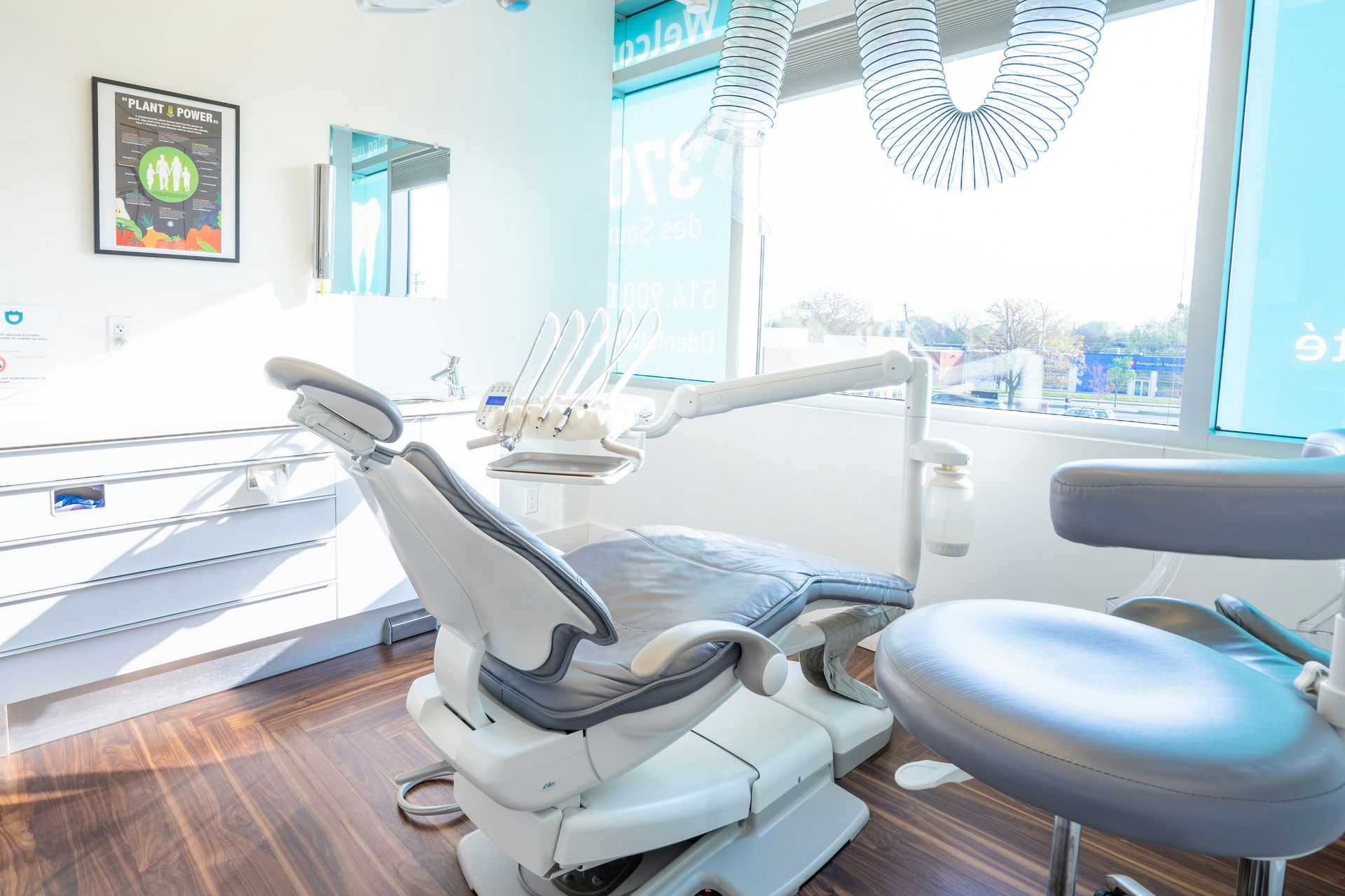 Dental office interior: dental chair, instruments, window, and examination stool in a bright room.