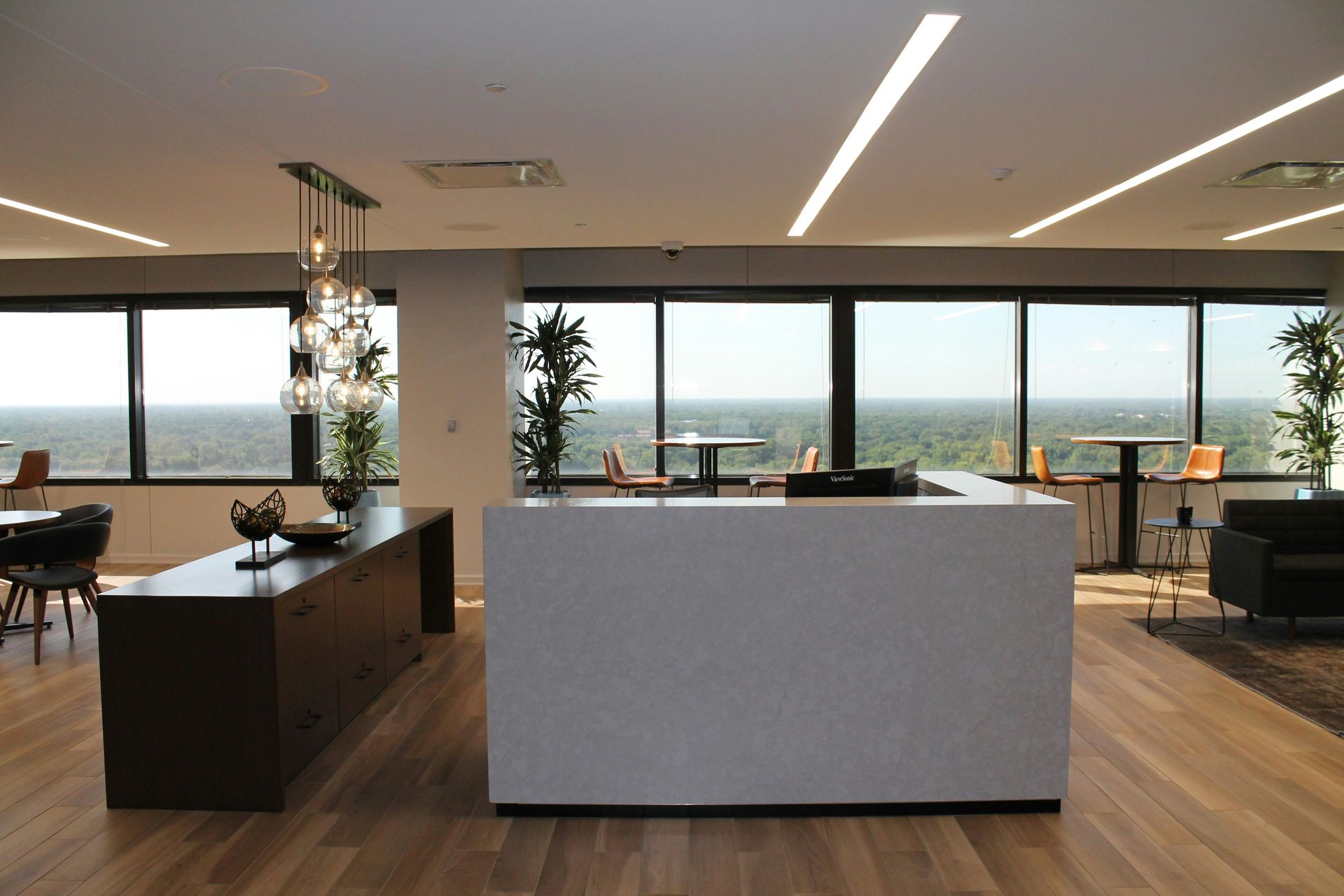 Modern office lounge with countertop and windows overlooking trees.