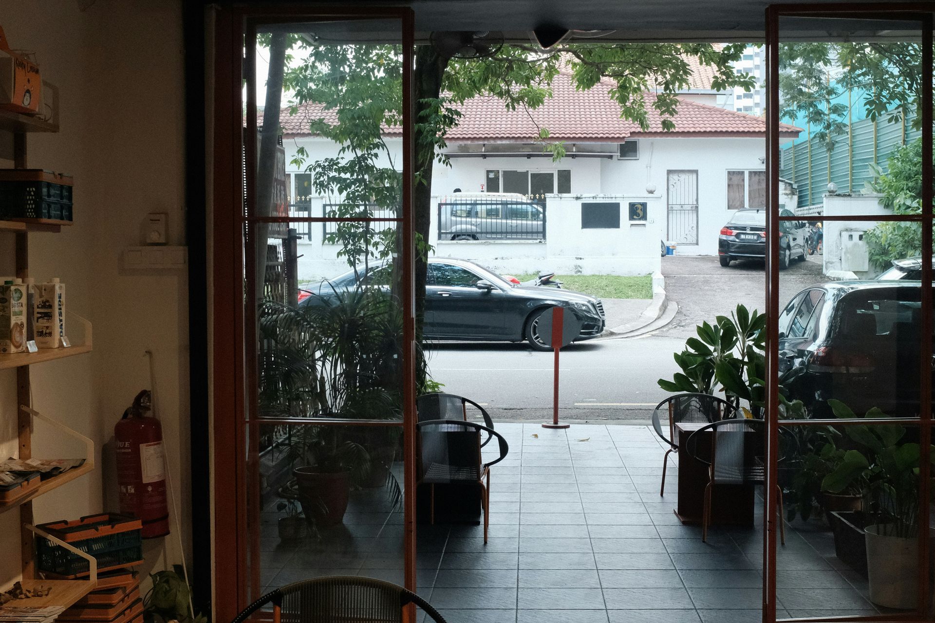 View from interior doorway to street; cars, buildings, and trees are visible outside.