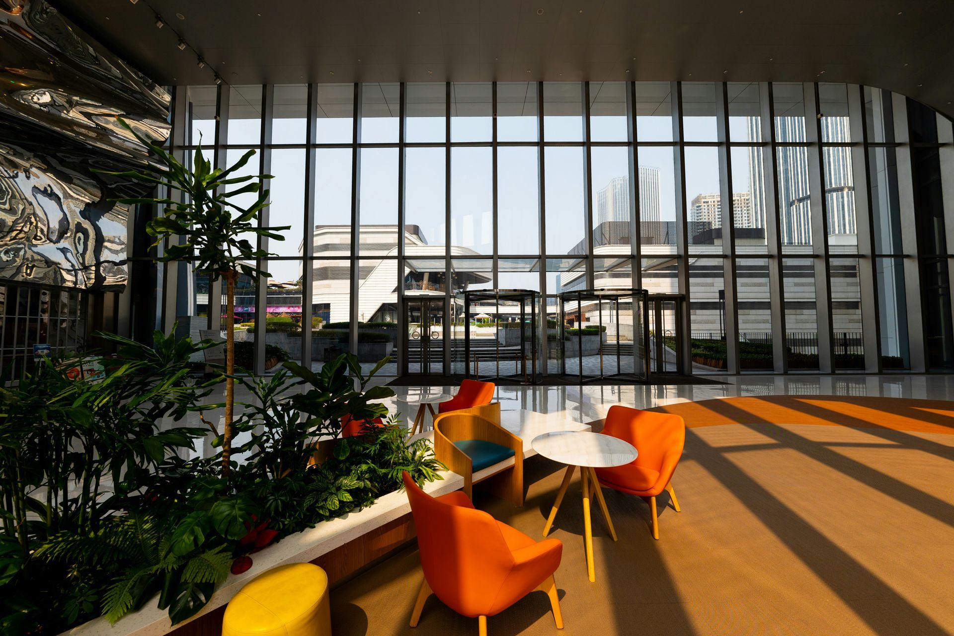 Interior view with seating area, large windows, and outdoor cityscape visible.