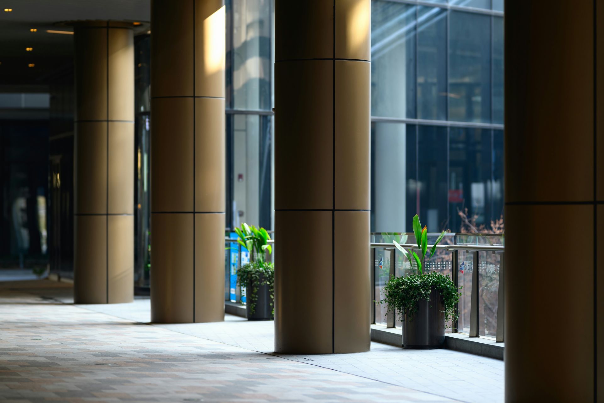 Columns in a modern building's outdoor walkway, with potted plants.