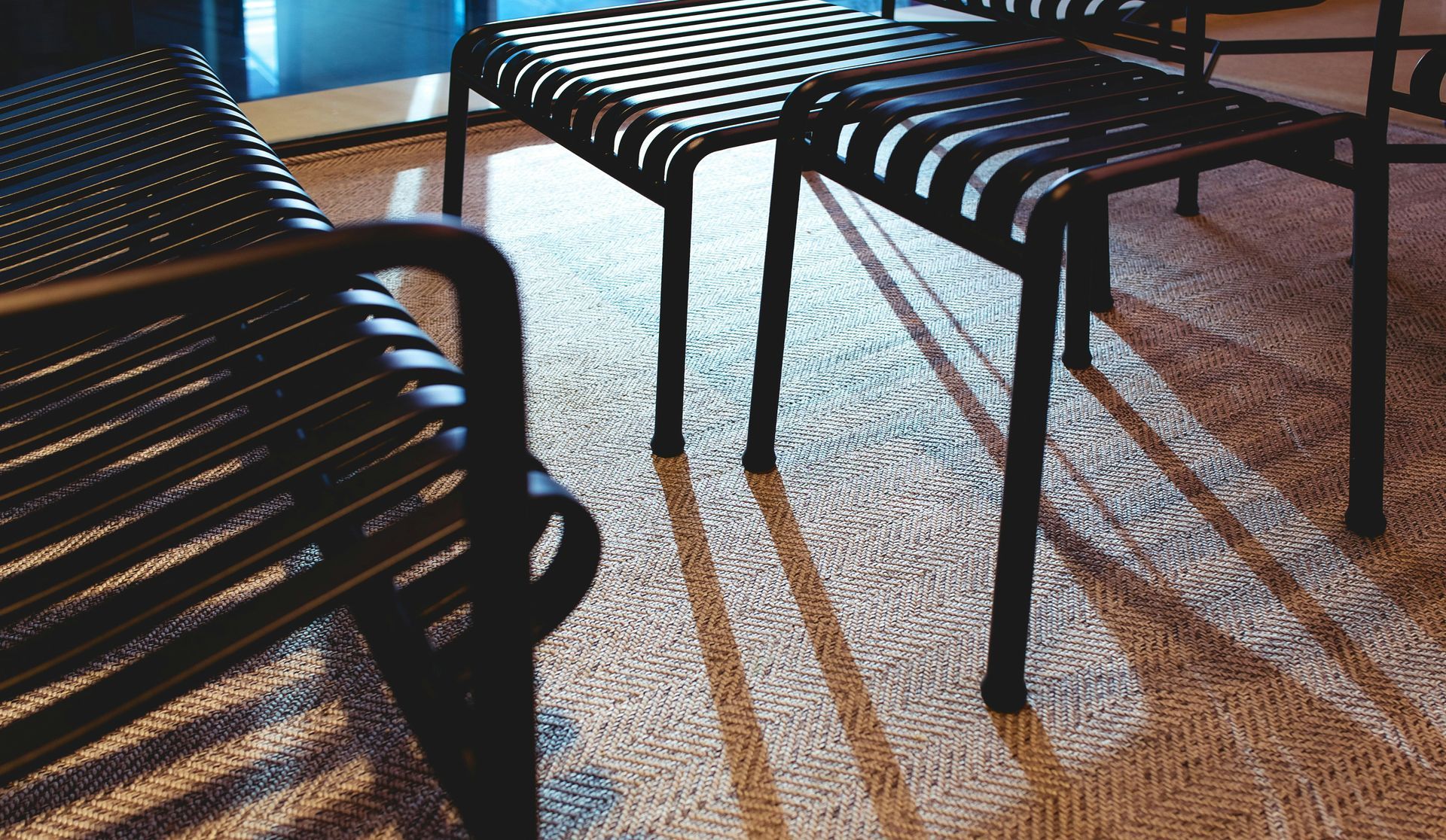 Black metal chairs casting shadows on a textured rug.