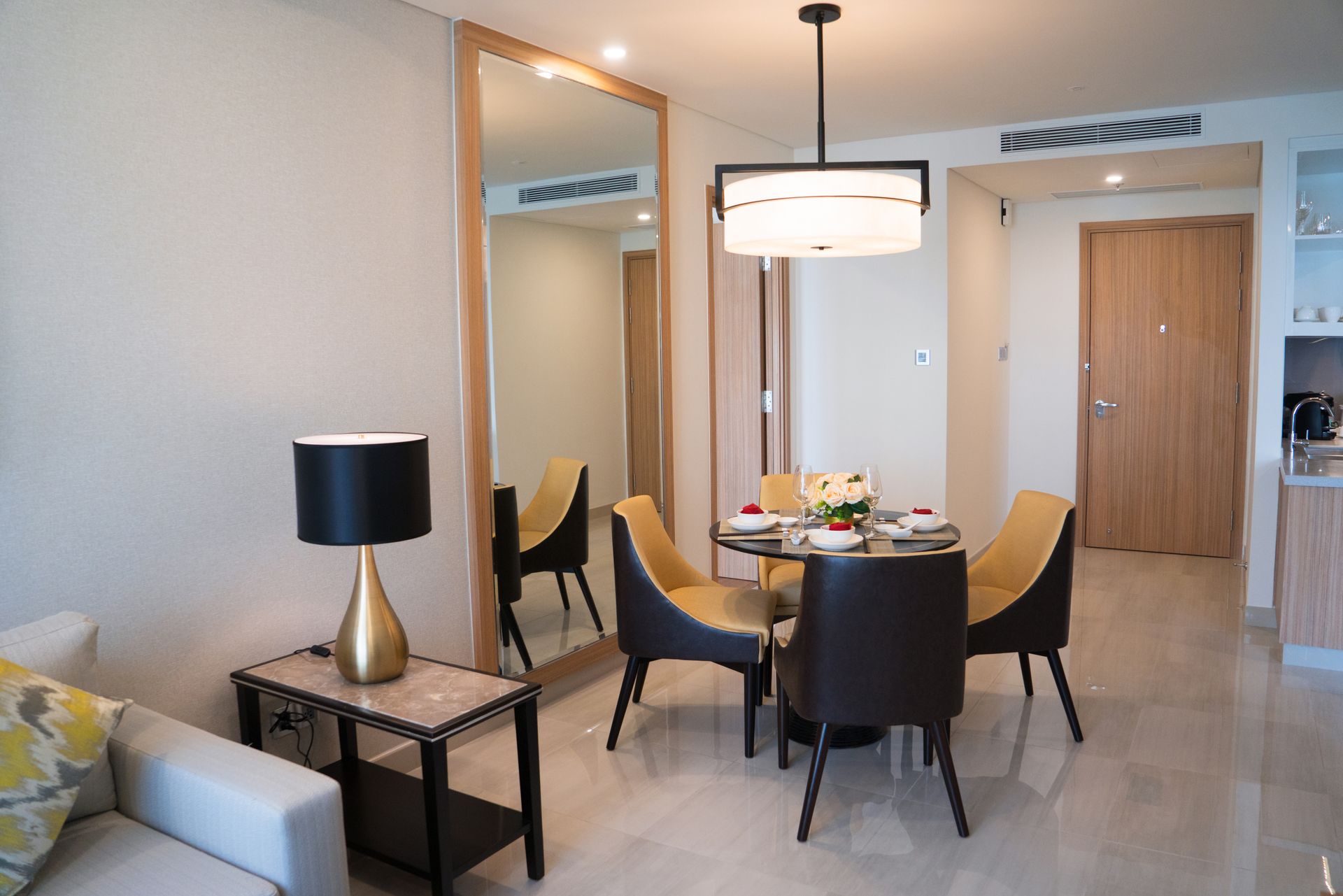 Dining area with table and chairs, mirror, and lamp.
