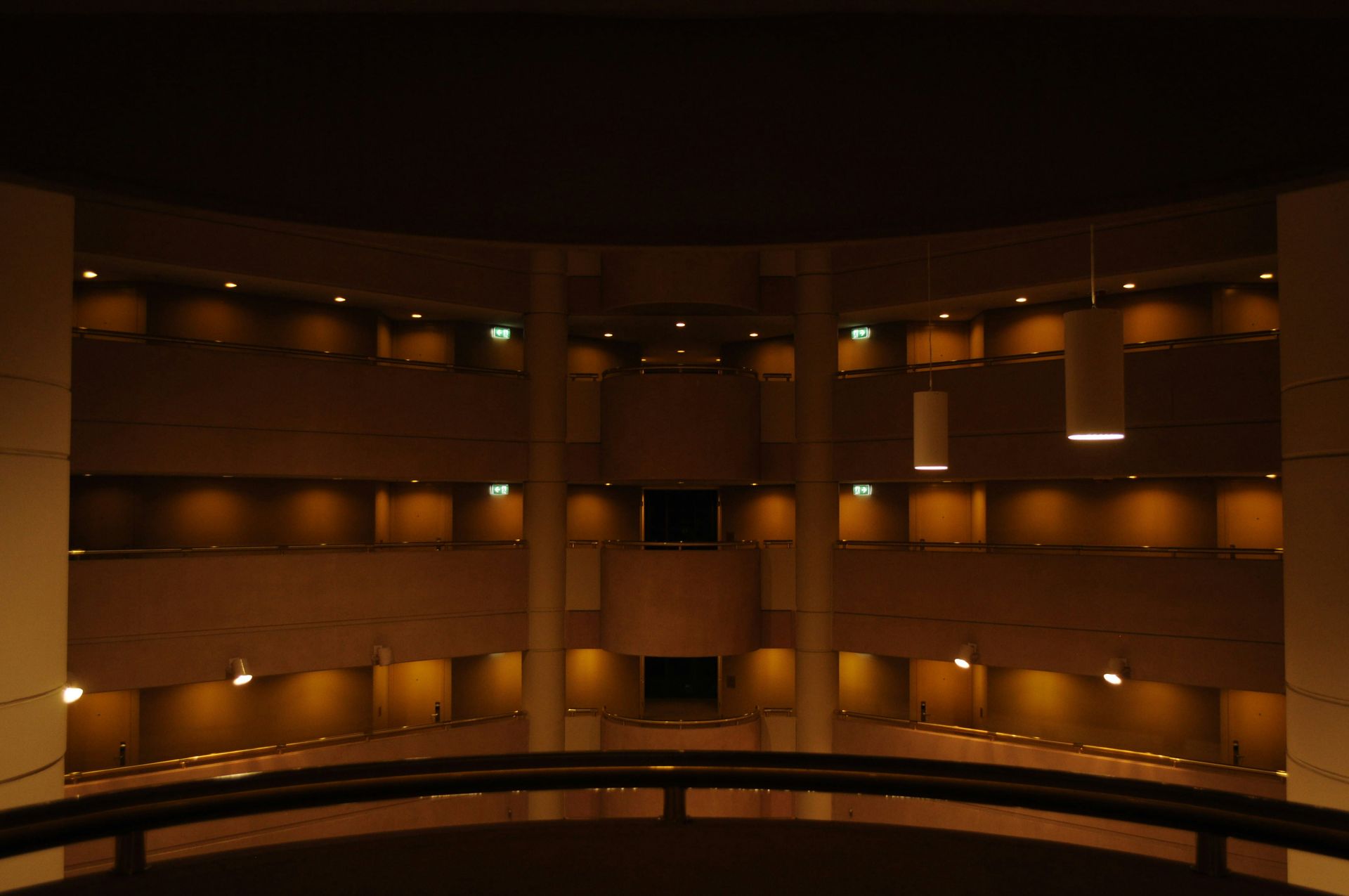 Interior view of a multi-story building, circular with balconies, soft lighting.