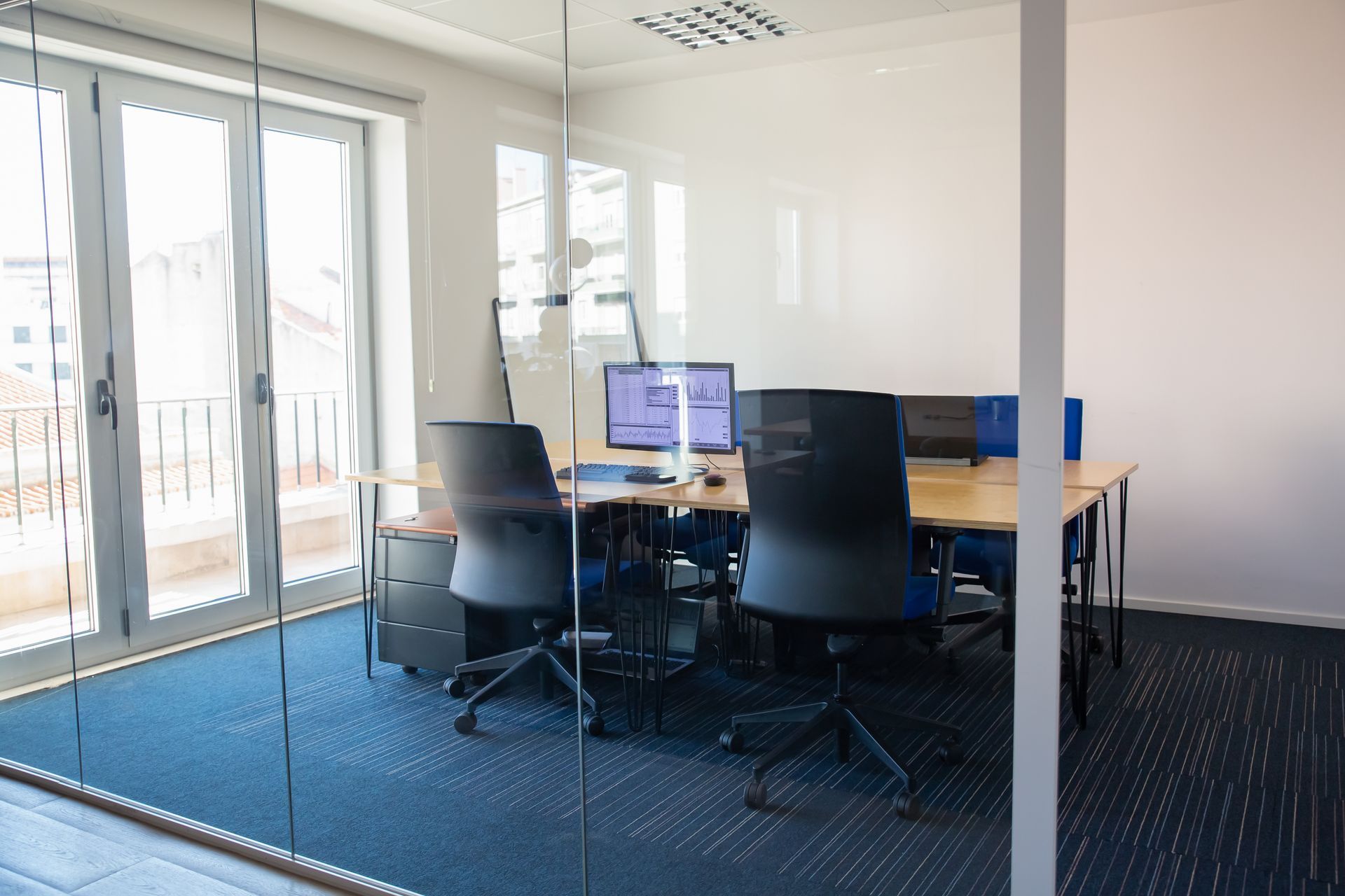 Office space with desks, chairs, computers, and a blue carpet.
