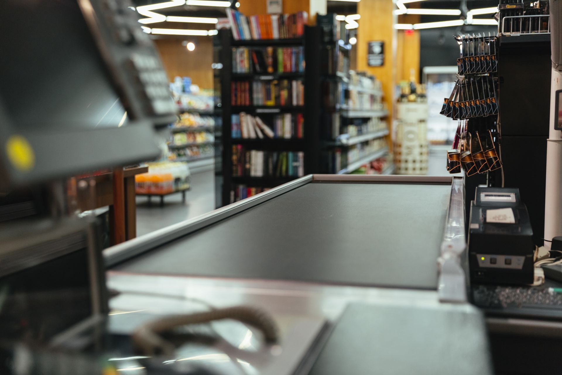 Cash register at a store checkout counter; shelves of books and merchandise in the background.