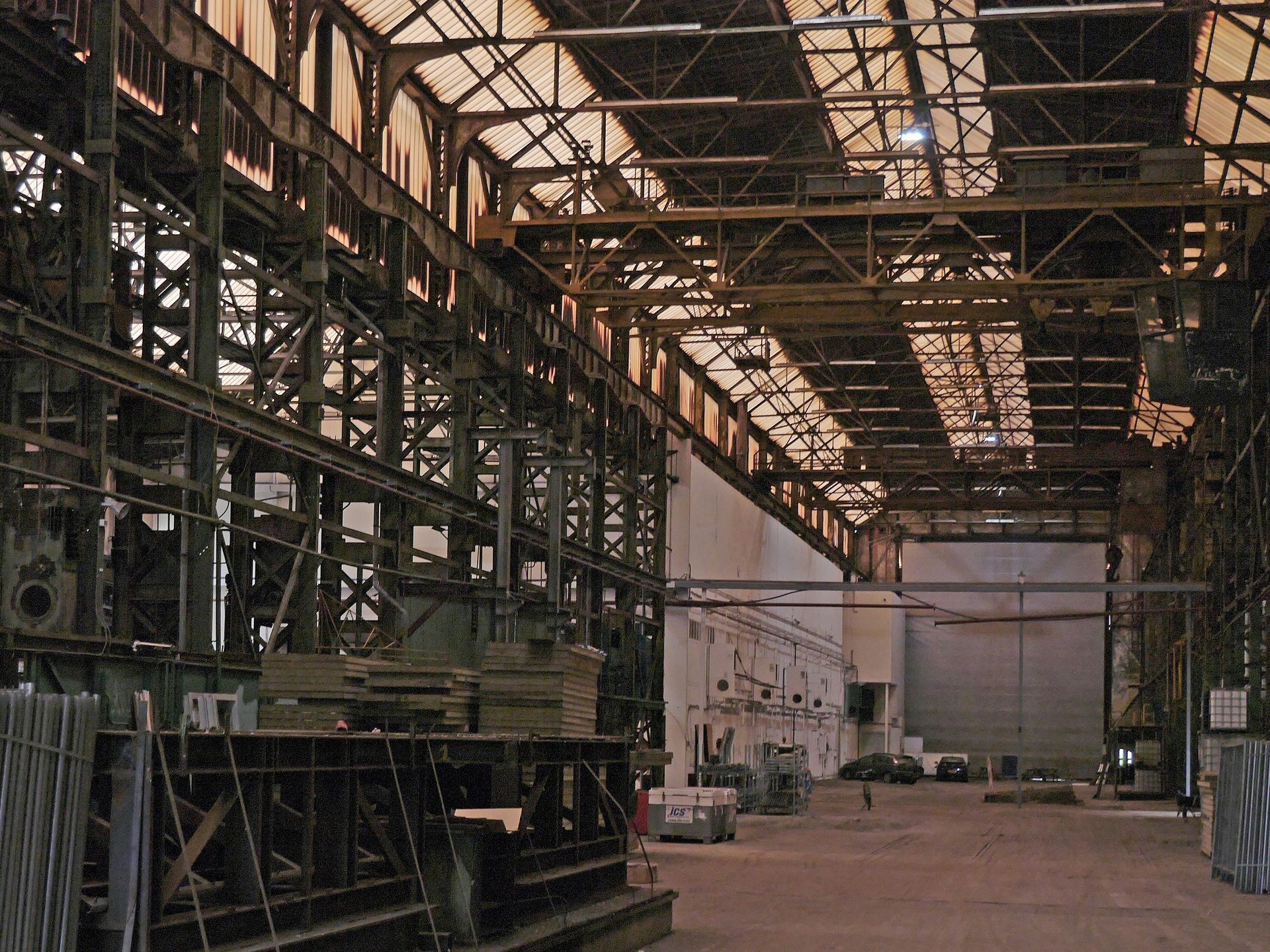Interior of a large industrial building, with metal framework, high ceiling, and large machinery.