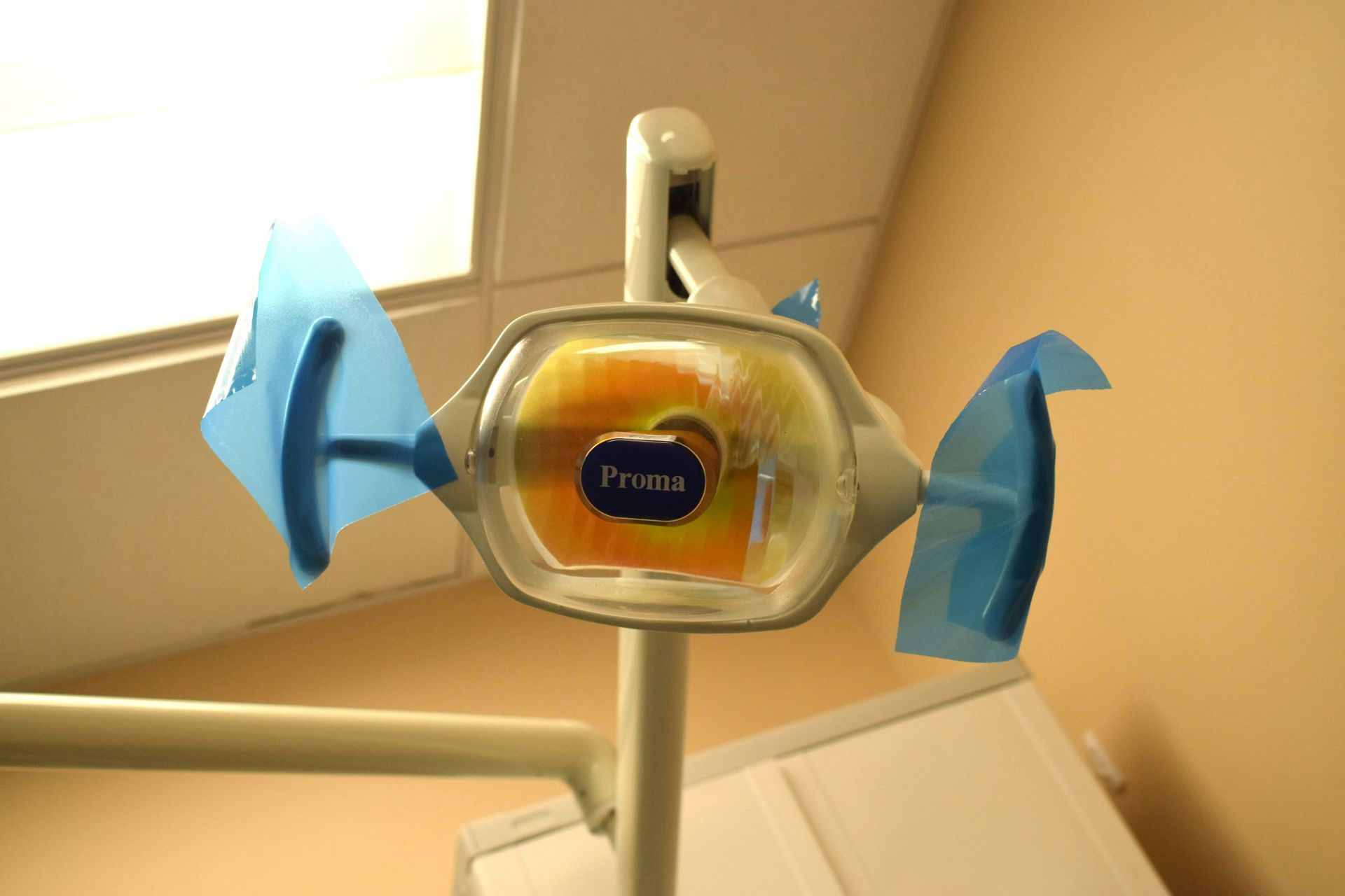 Dentist's lamp with blue protective shields. The lamp is attached to a vertical arm; the setting is a dental office.