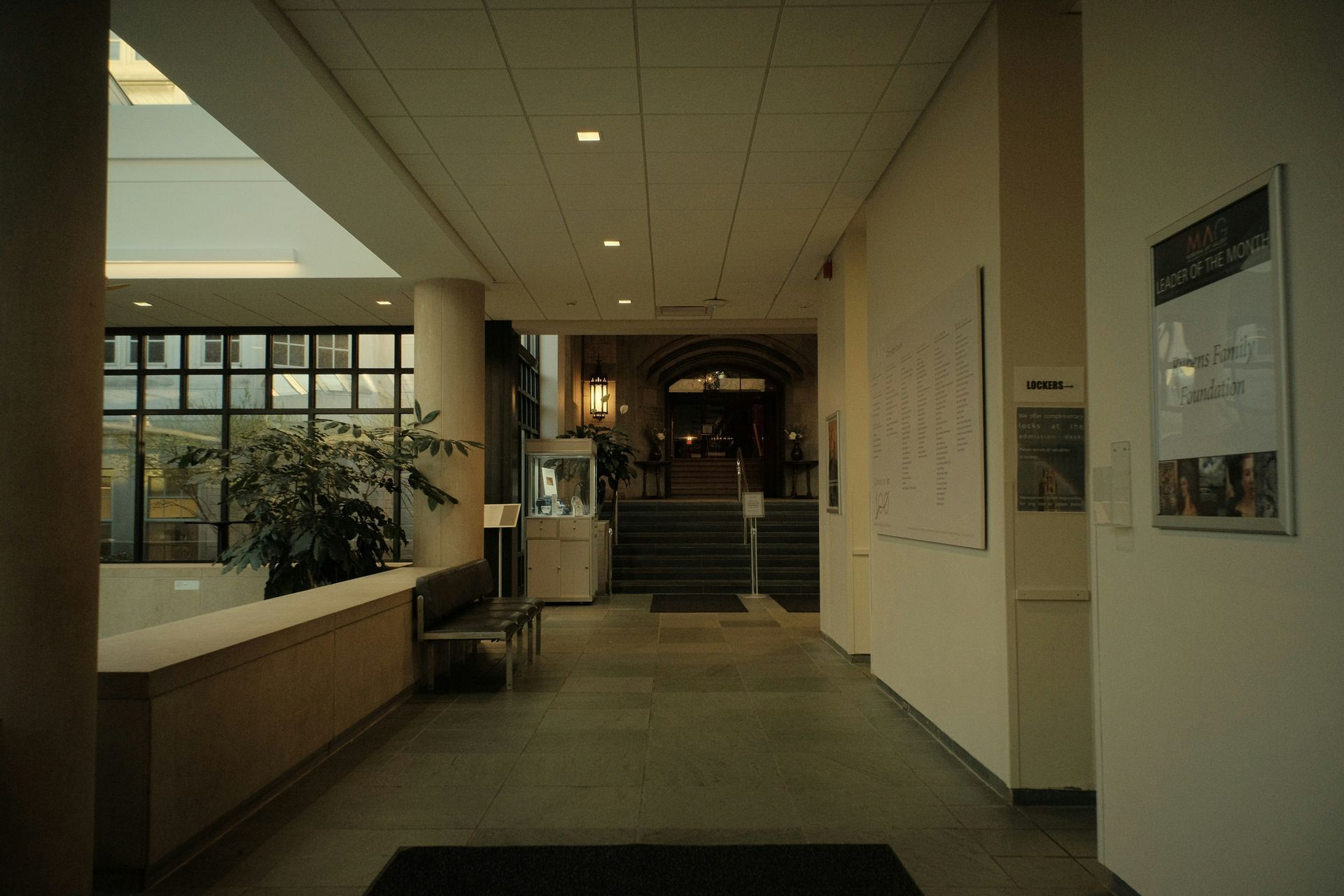 Hallway with beige walls, a view of stairs and entrance, a plant, and framed papers.
