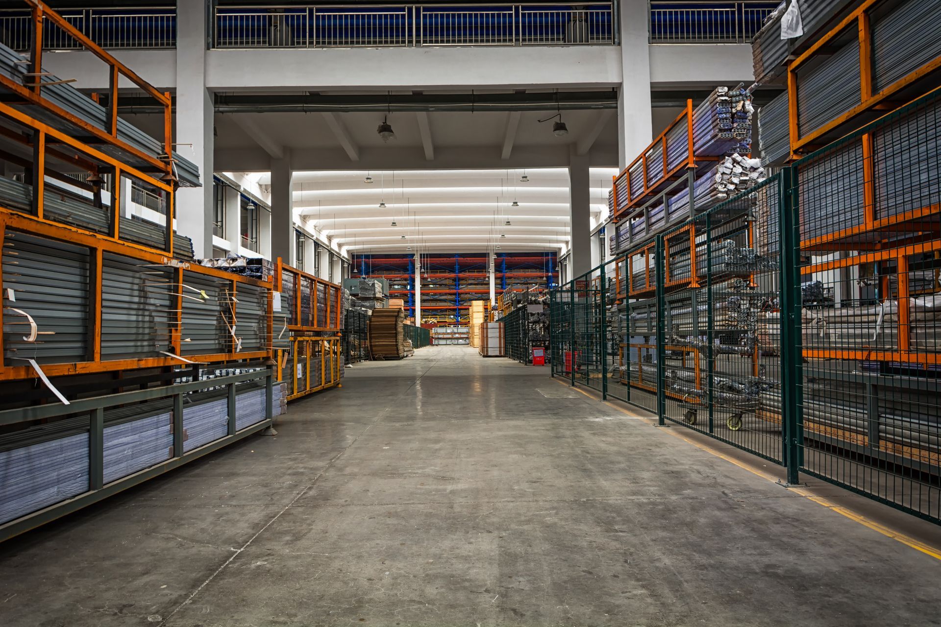 Warehouse interior with rows of metal shelves filled with materials. Concrete floor, high ceilings.