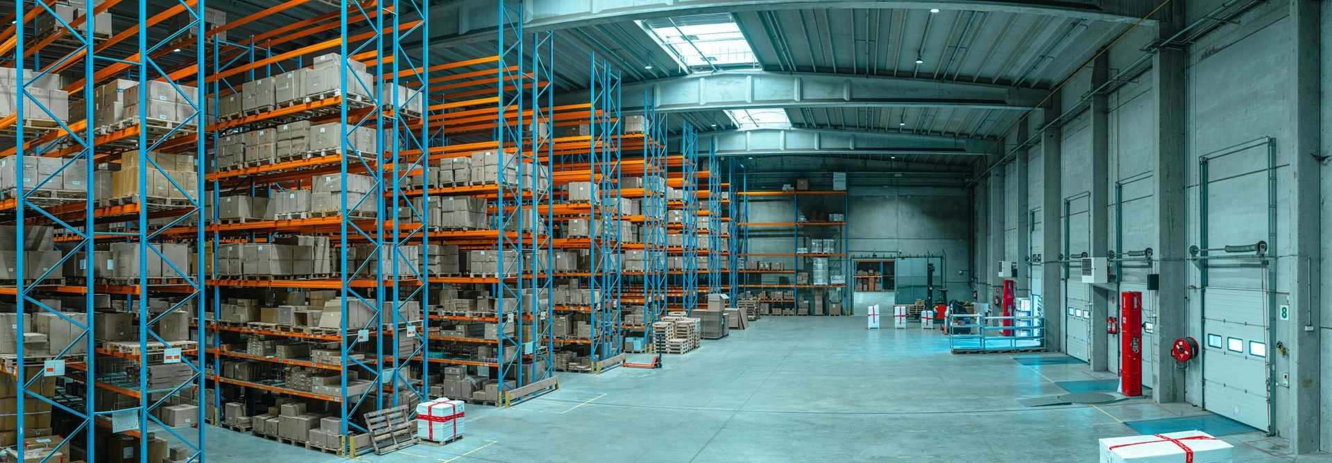 Warehouse interior with shelves of packaged goods and loading dock doors.