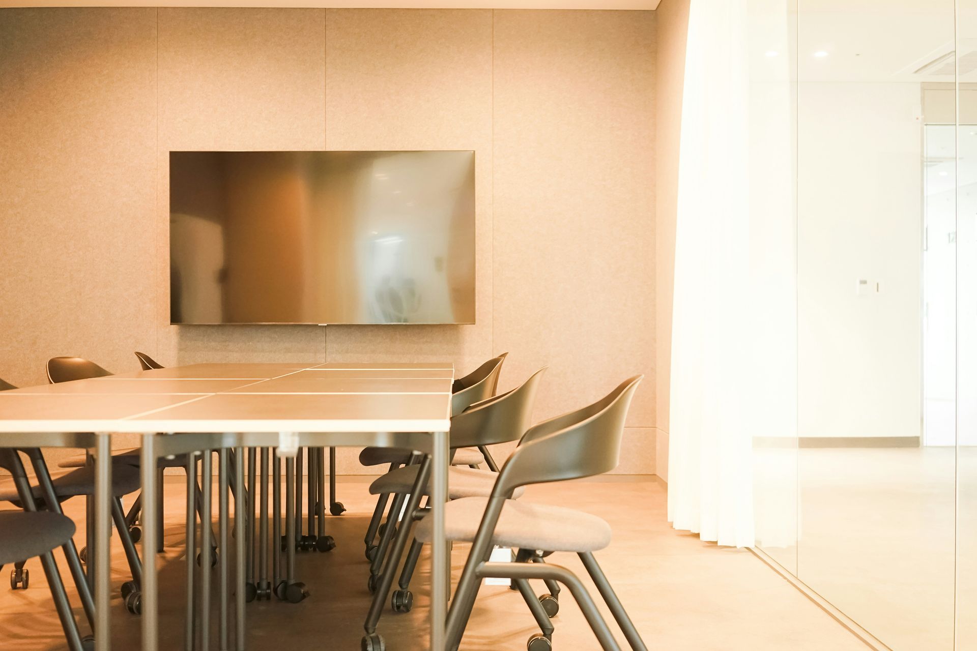 Conference room with a rectangular table and chairs, and a large TV on the wall.