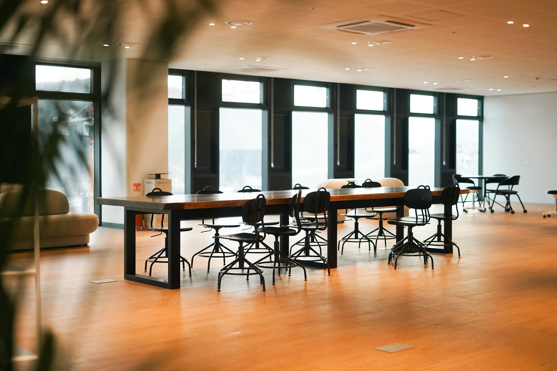 A large, open office space with a long table and chairs in front of large windows.