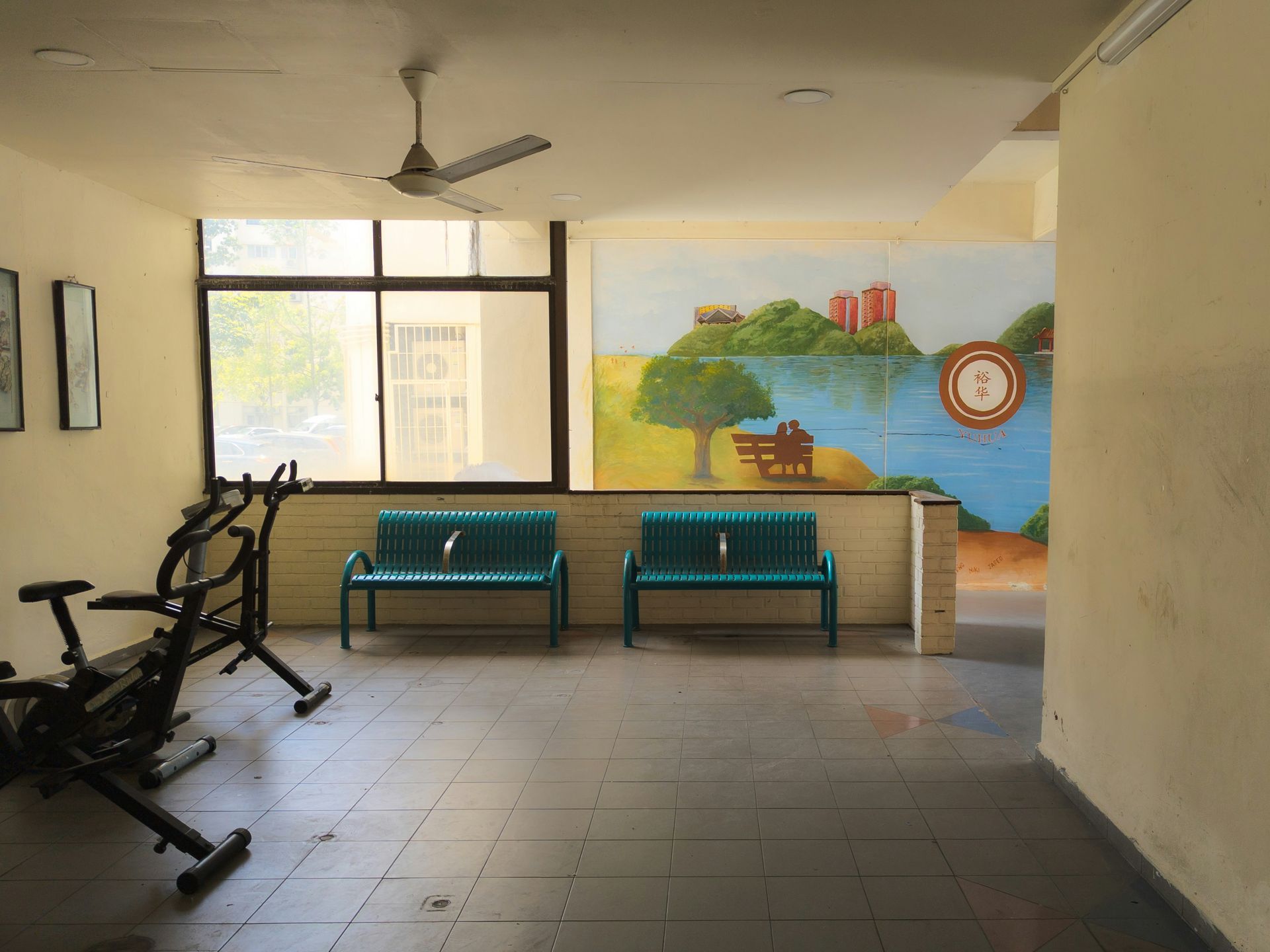 Gym area with exercise bikes, two green benches, and a mural of a lake scene.