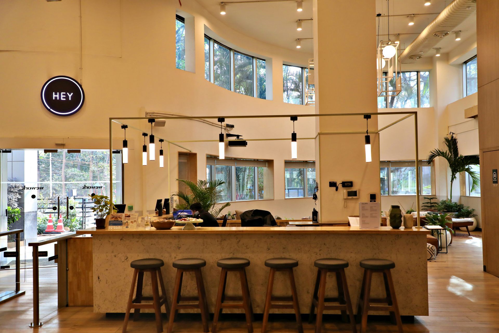 A well-lit cafe interior with a bar, stools, and logo sign.