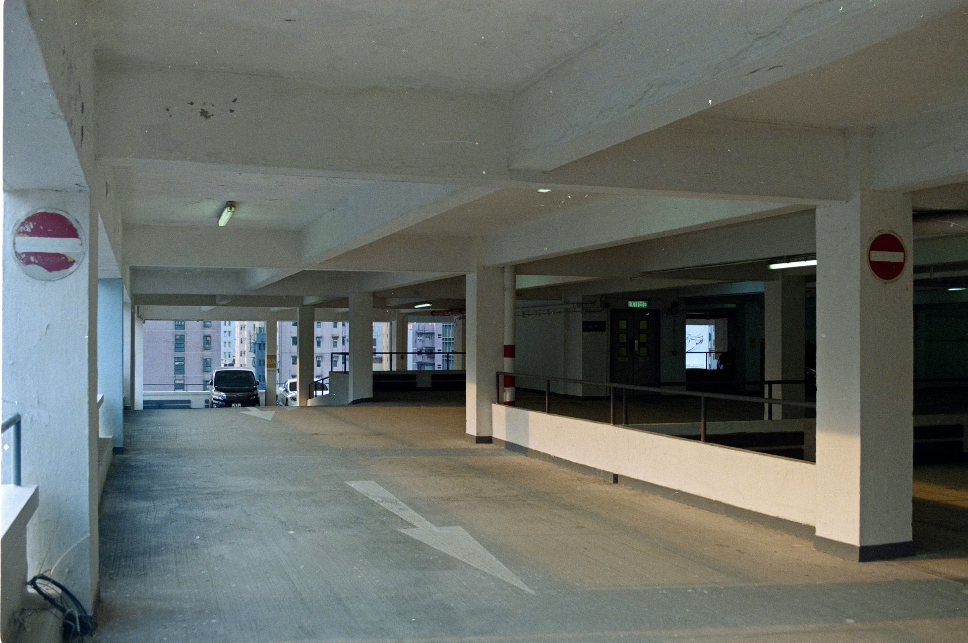 Interior of an empty parking garage. White concrete columns, ceiling, and floor. No entry signs visible.