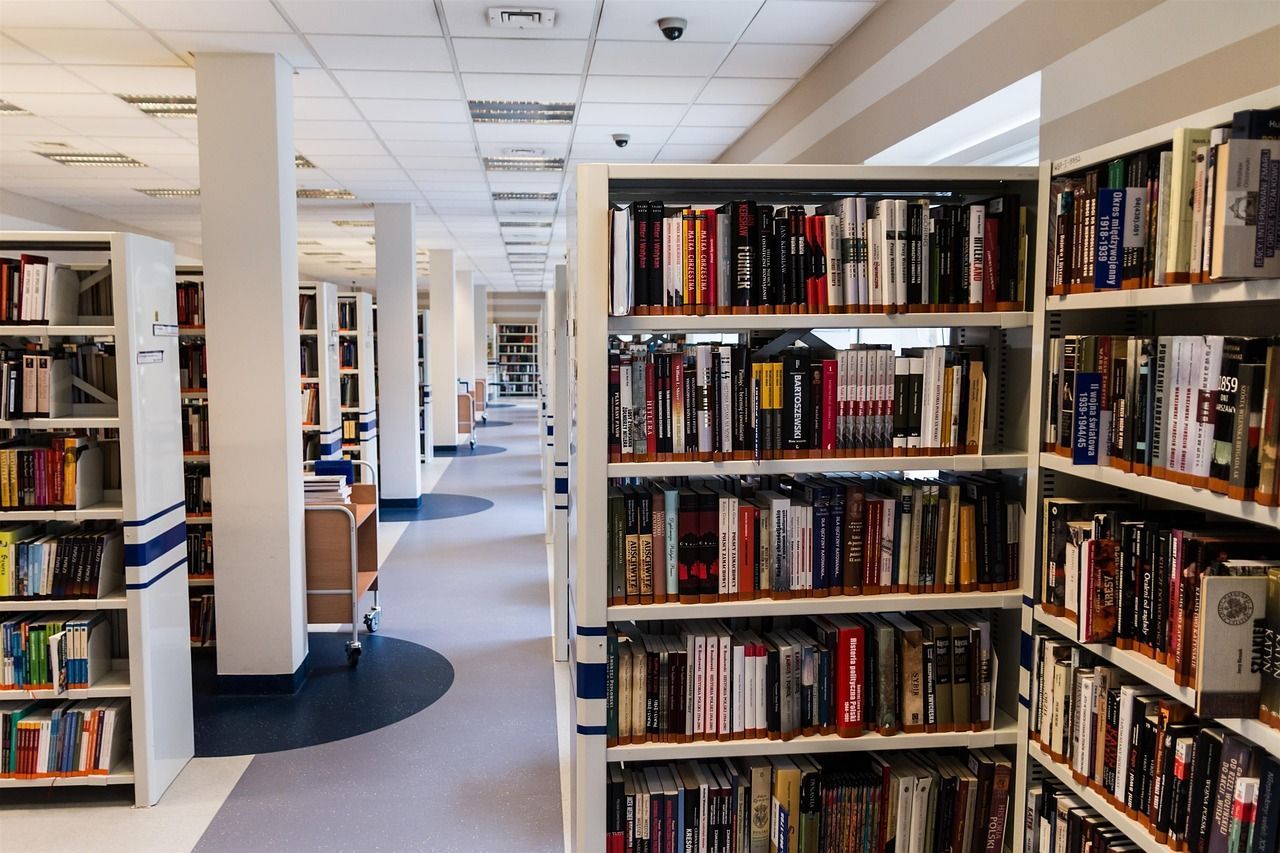 Library interior with rows of bookshelves filled with books. White shelving and columns with a long hallway.