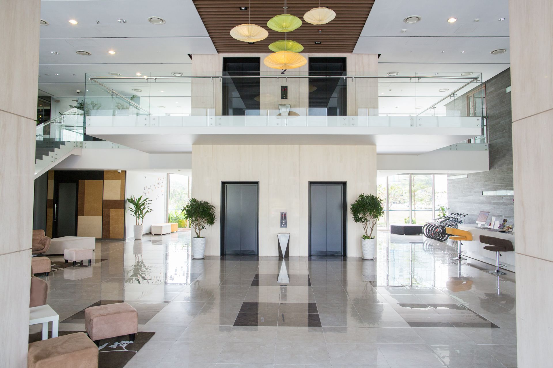 Lobby with elevators, seating, and a second-floor walkway. Bright and airy space with a modern design.
