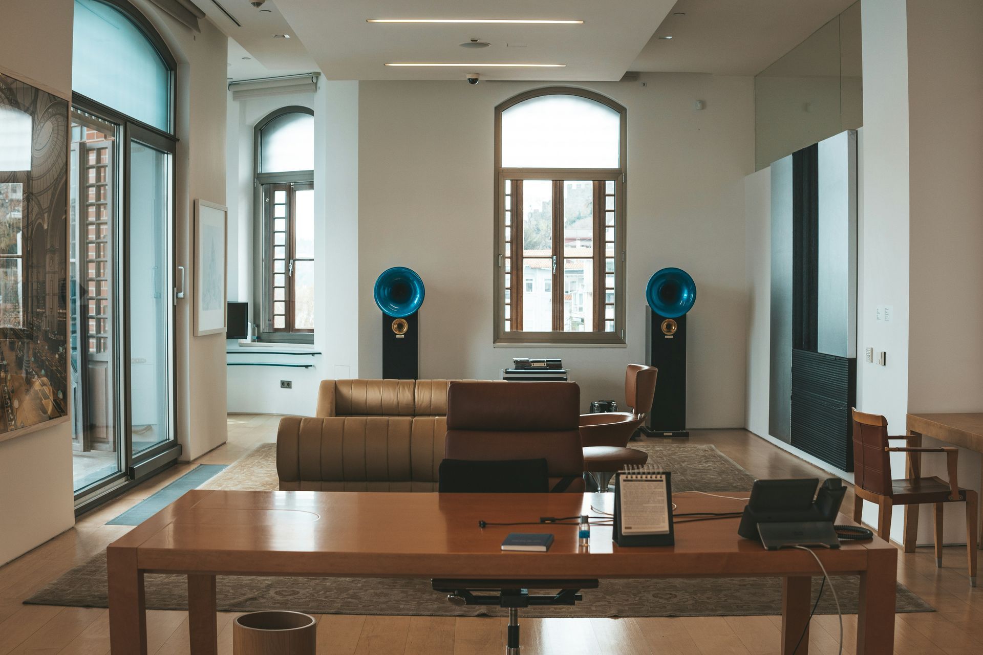 Spacious room with large windows, leather furniture, and distinctive blue horn speakers flanking a central window.