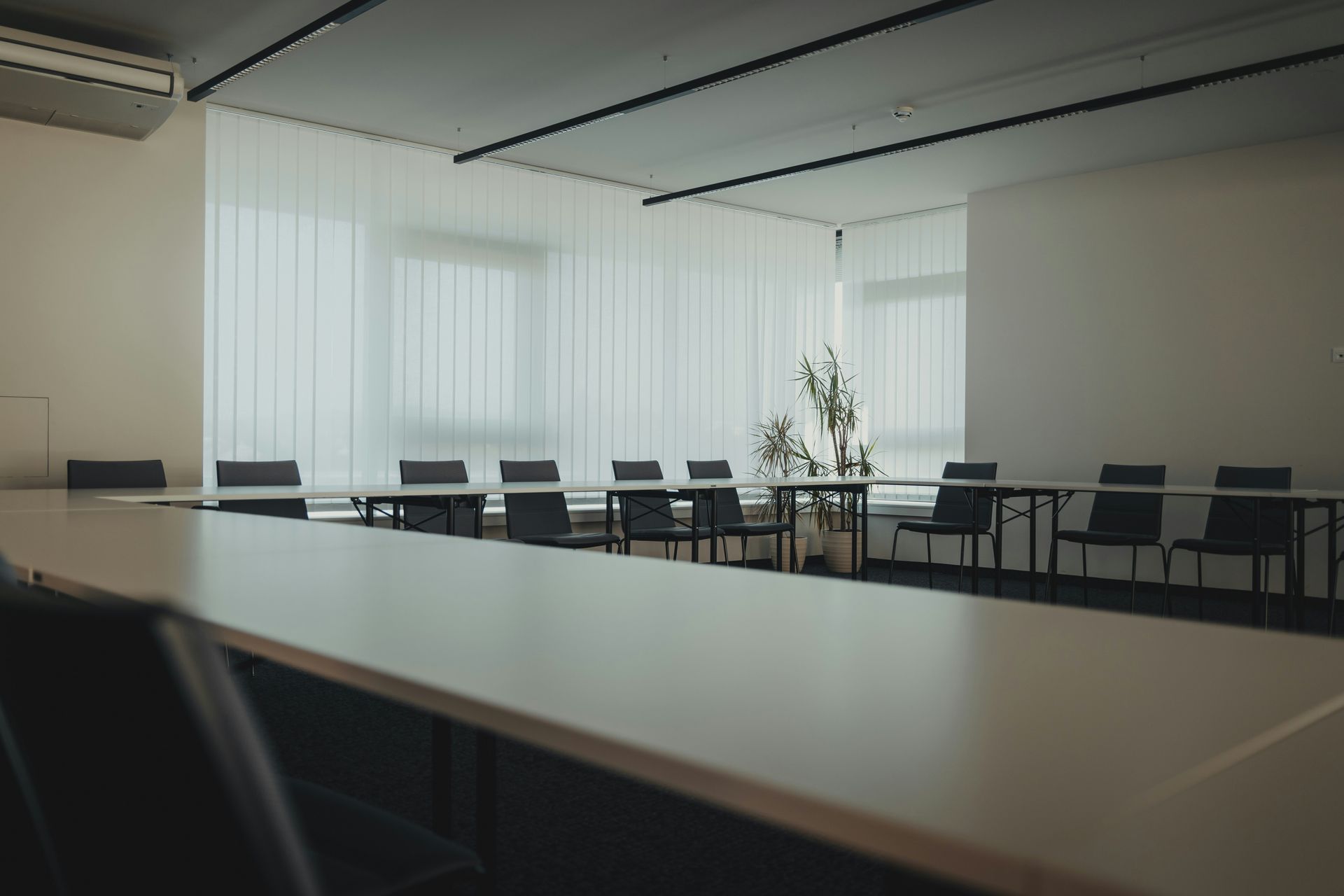 Empty, bright conference room with long table, chairs, and window with blinds.