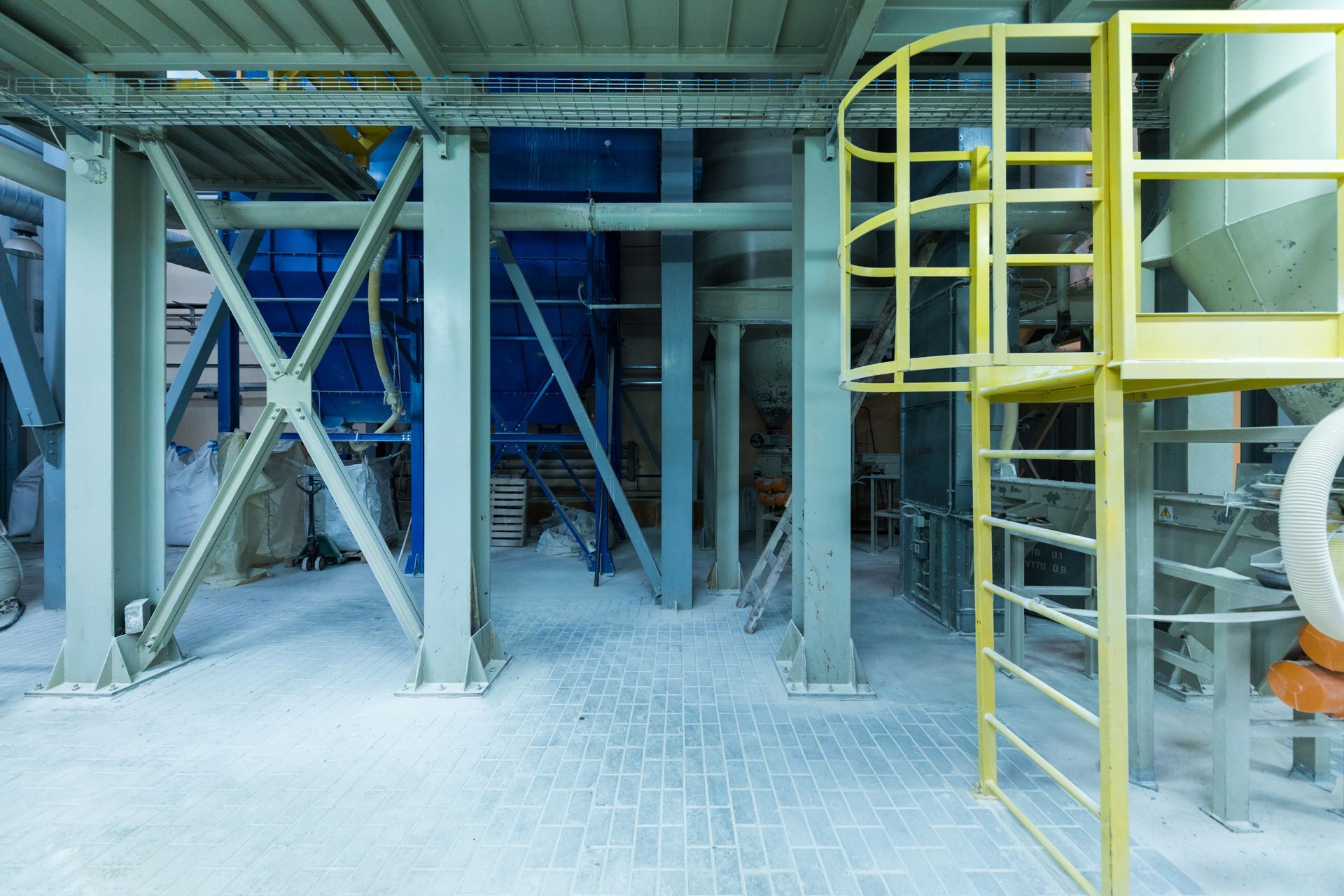 Industrial interior with support beams, yellow ladder, and powdery white substance on the floor.