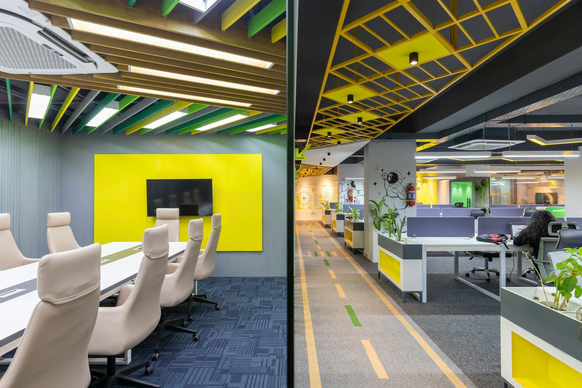 Modern office interior with conference room and open workspace; yellow and gray color scheme.