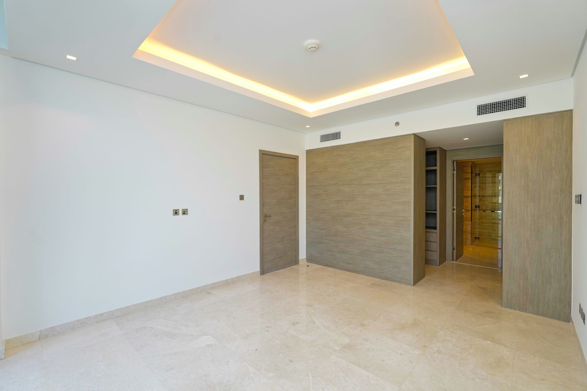 Empty modern room with light-colored walls, marble floor, and recessed ceiling lighting.