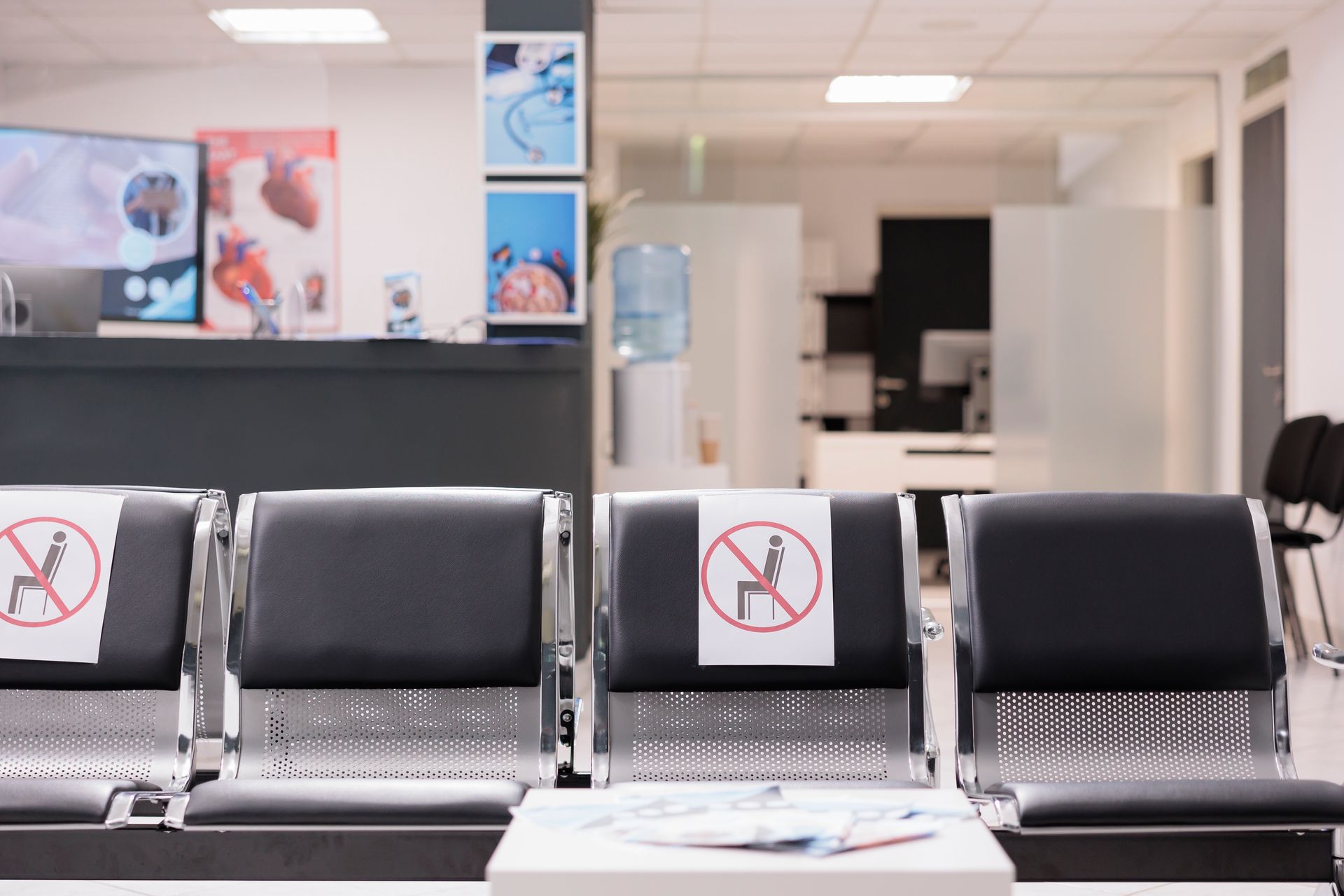A waiting room with black chairs, some marked